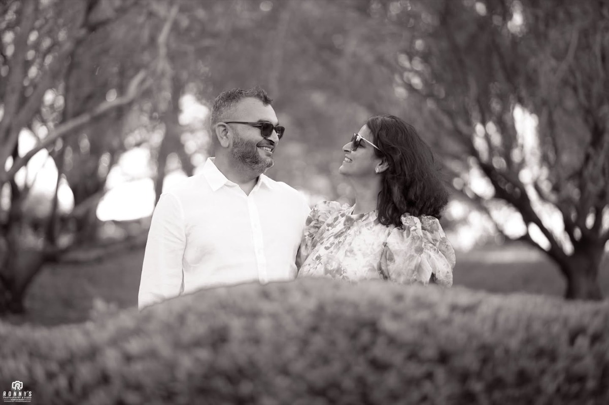 Black and white portrait of a couple smiling at each other among the trees
